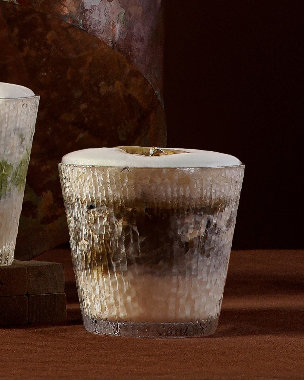 A frosted glass of hojicha latte with layers of roasted tea and milk.
